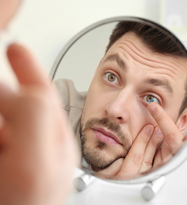 Patient putting in eye contact with mirror